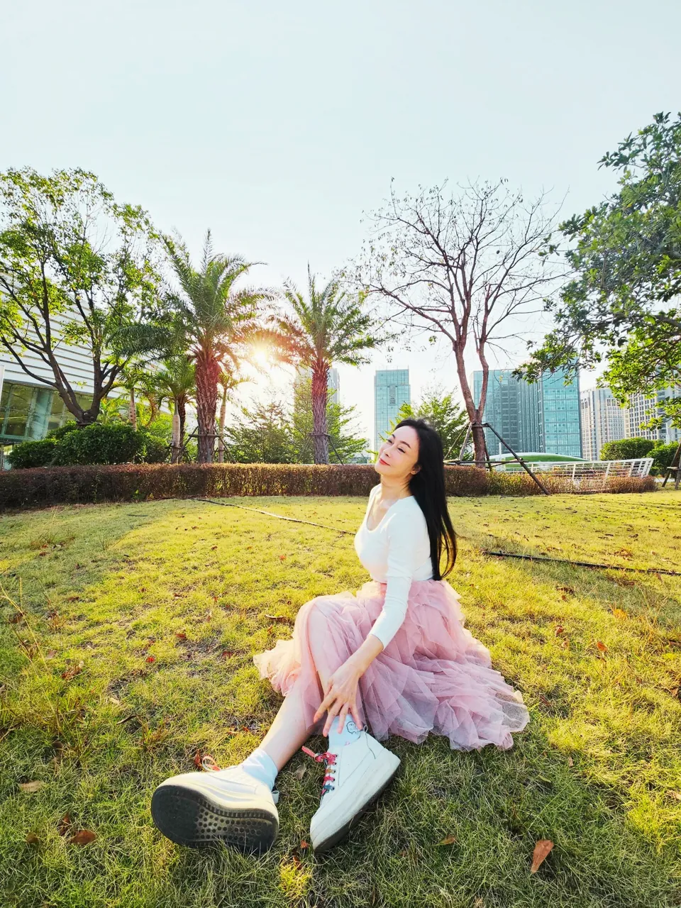 顧婕老師坐在陽光下的草地上